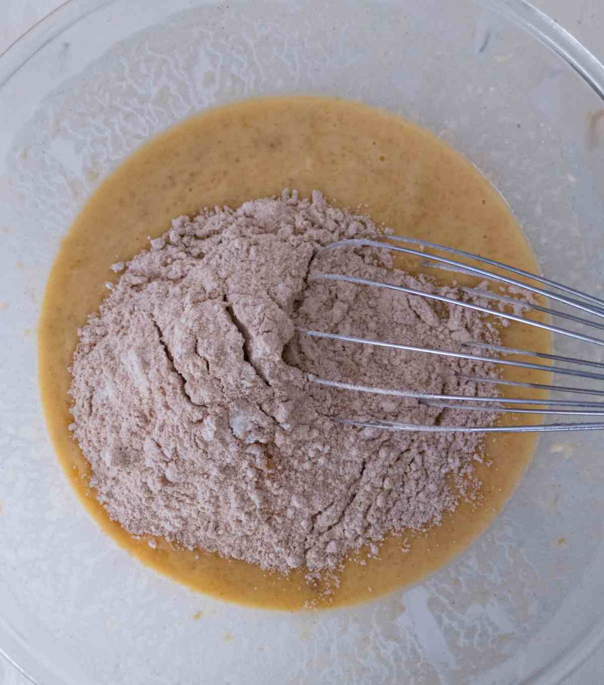 Dry ingredients in the bowl with wet ingredients with a whisk.