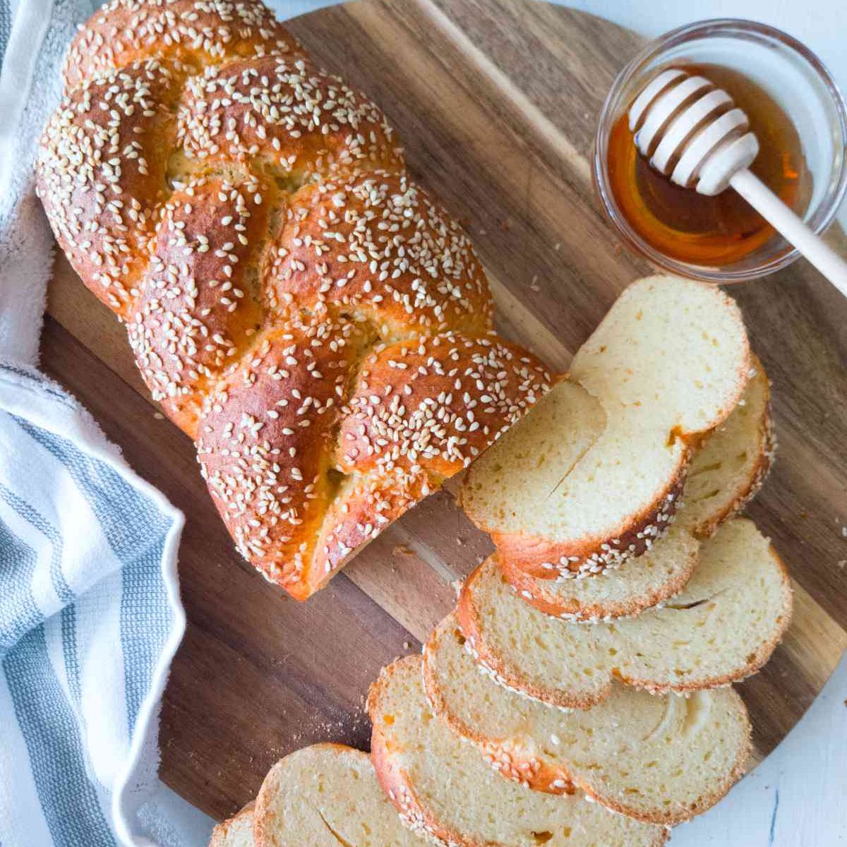 Gluten-free sourdough challah on a cutting board with honey on the side.