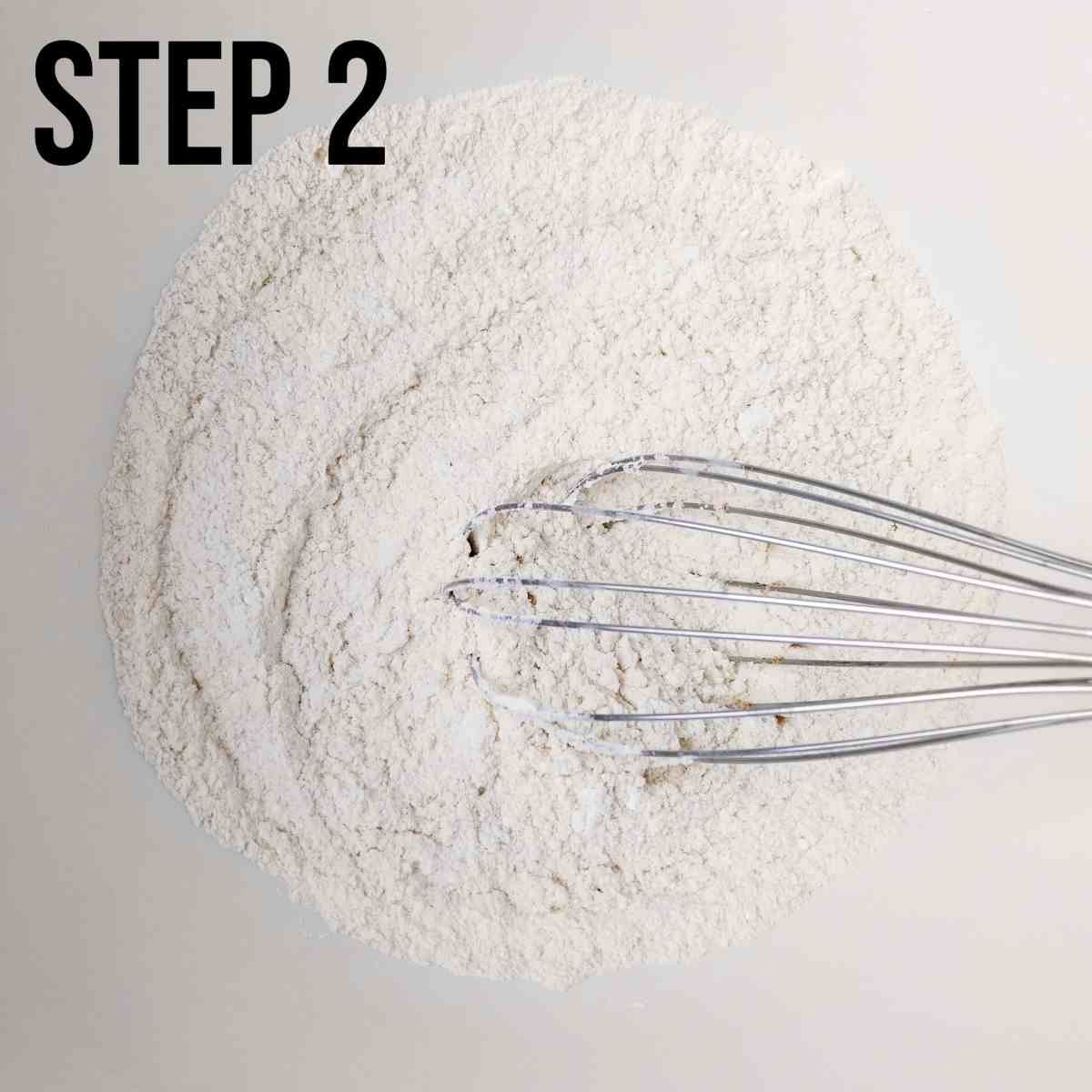 Mixing the dry ingredients in a large white bowl with a whisk.