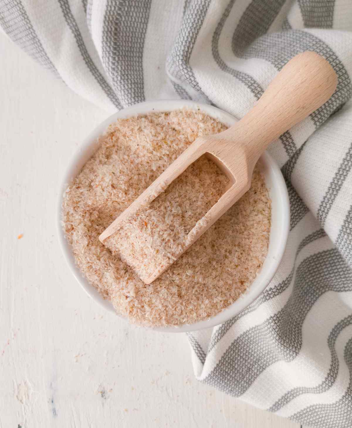 Psyllium husk in a small bowl with a wooden spoon.