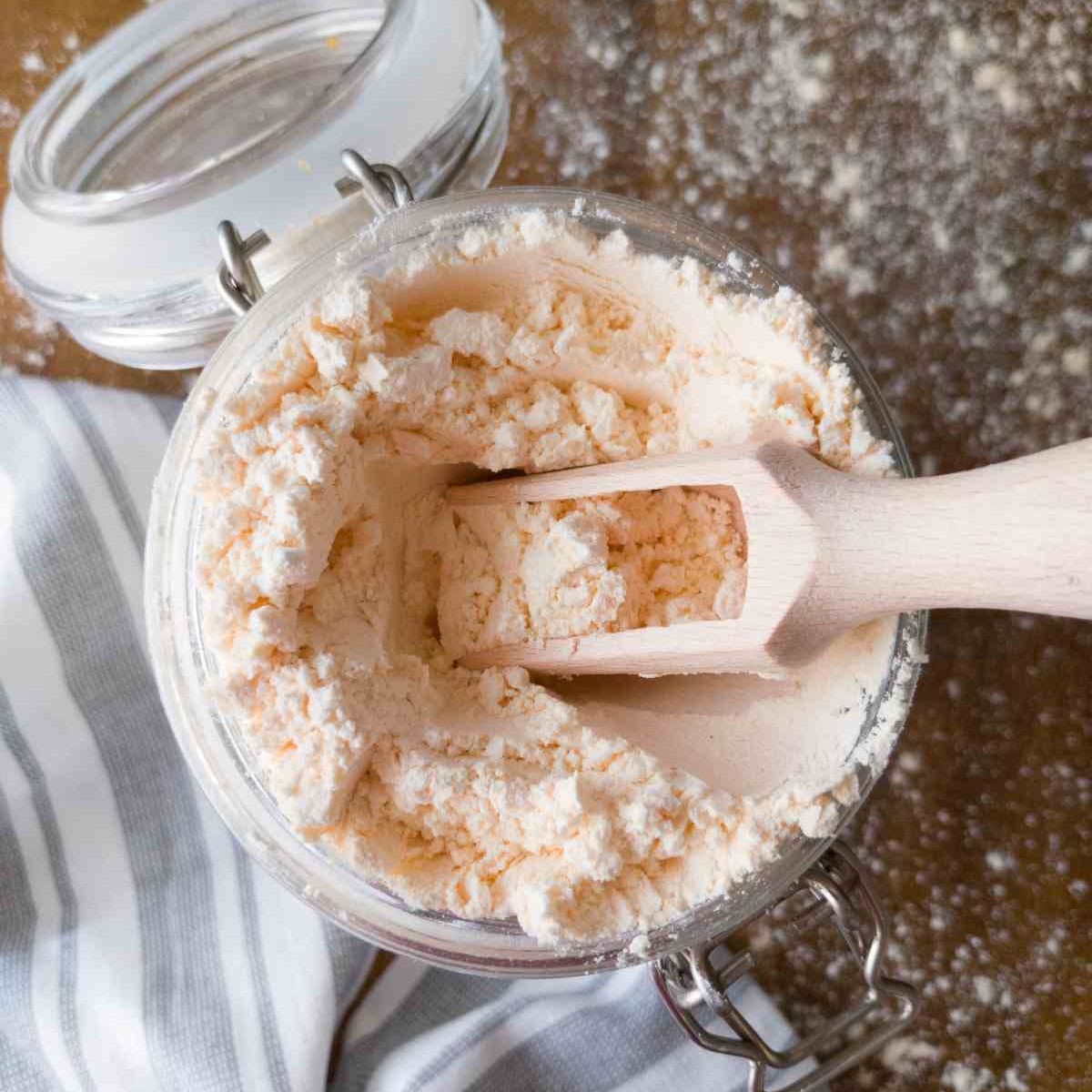 Rice-free gluten-free flour in a large glass jar with a wooden spoon.