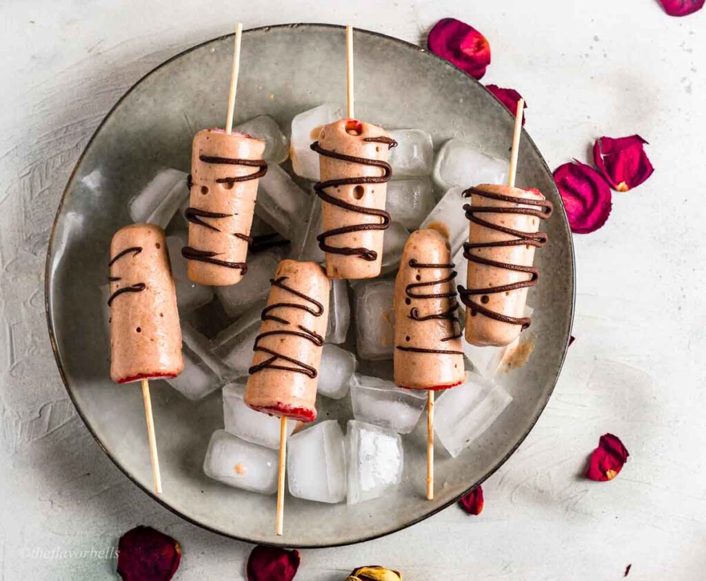 Gluten and sugar free banana popsicles on a plate with chocolate drizzle.