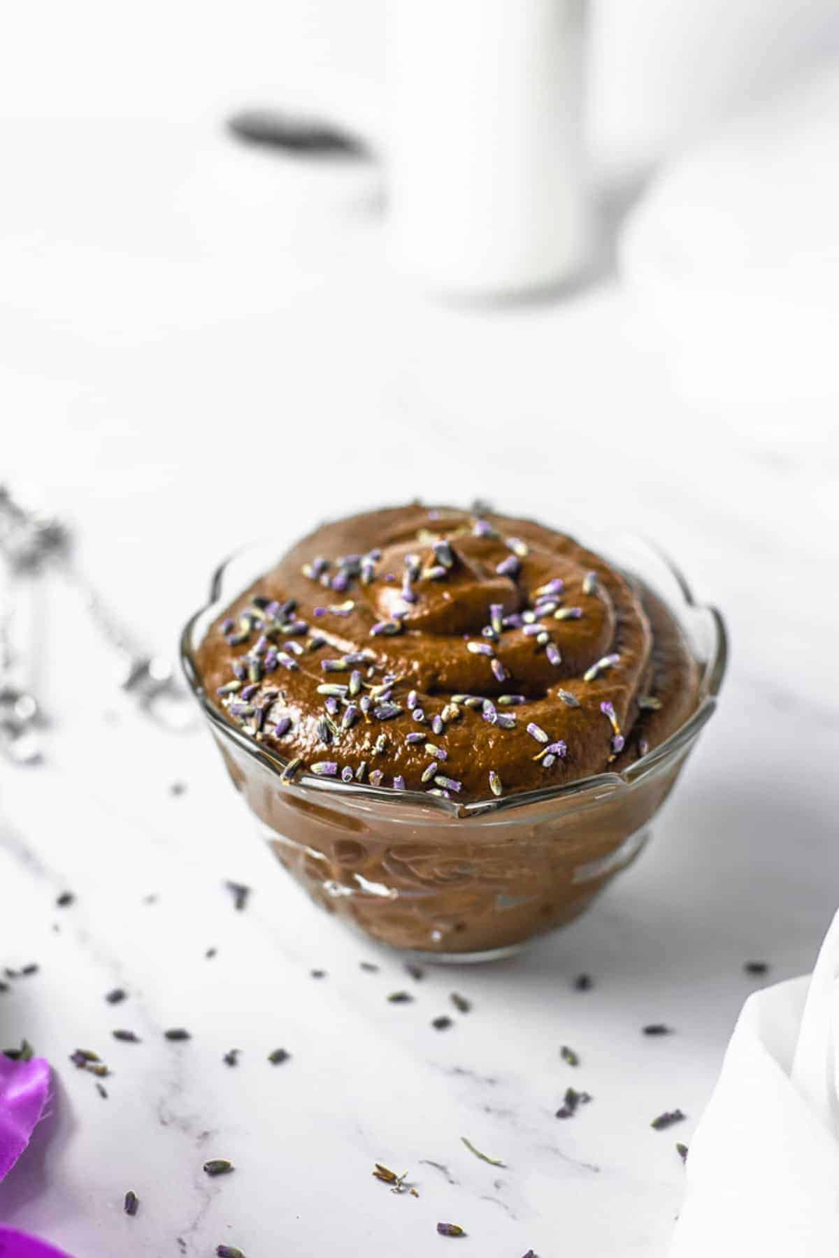 Avocado chocoltae sugar free mousse in a glass bowl on a white table surface.