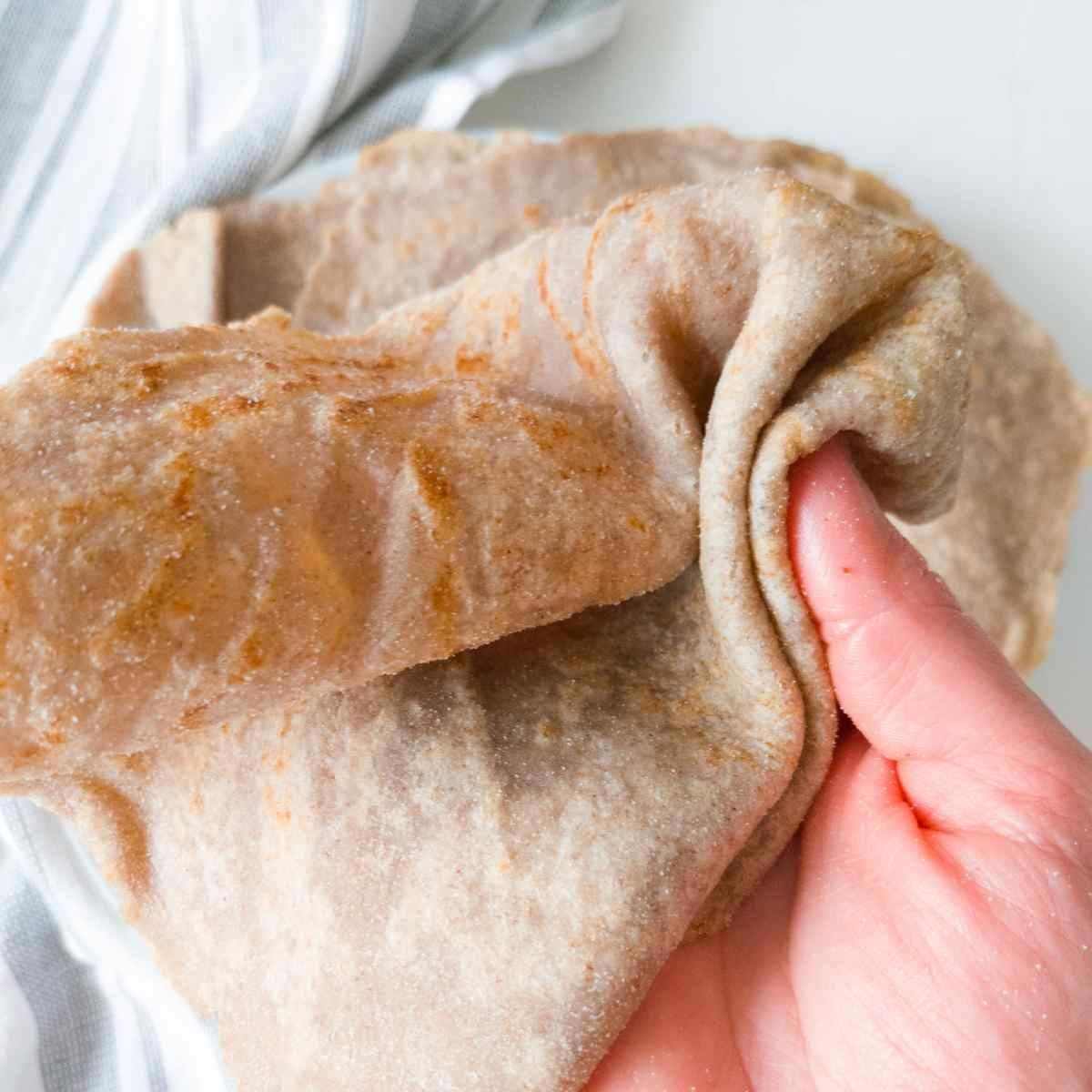 A buckwheat tortilla held by a hand up close.