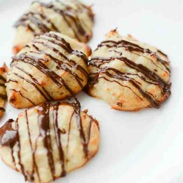 A few coconut macaroons with chocolate drizzle on a white background.