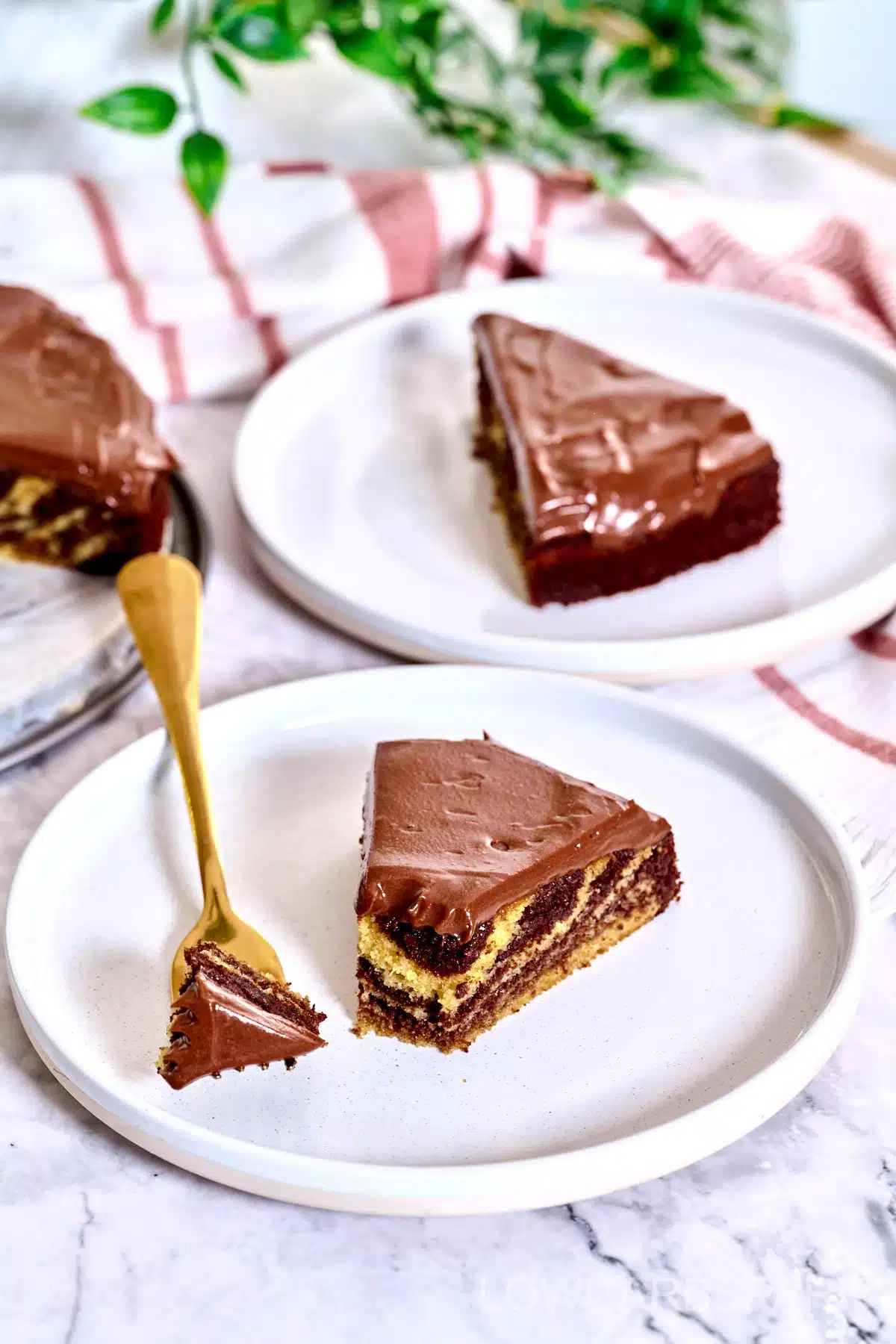 Two slices of zebra cake on two separate plates.