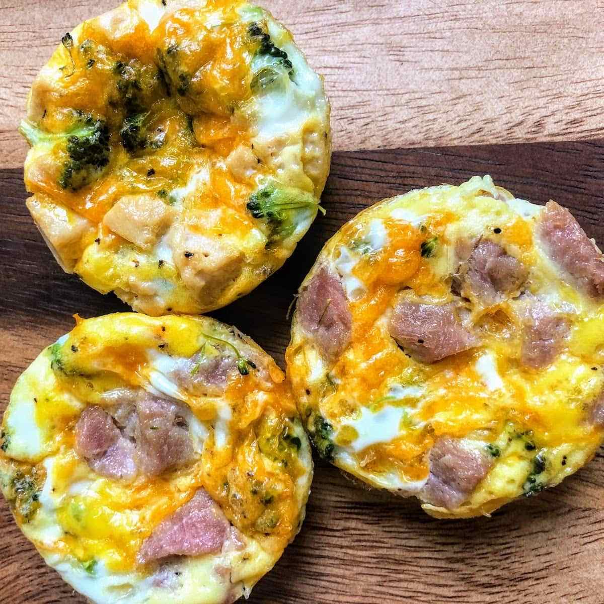 Egg bites with ham and cheese, three on a table.