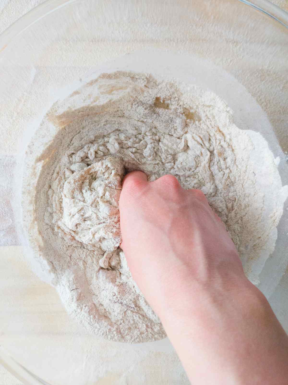 Mixing the dough by hand in a large glass bowl.