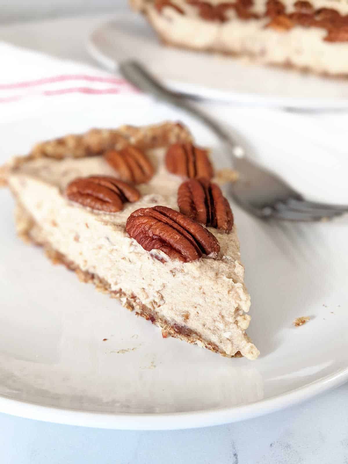 Pecan cream pie slice on a plate with a fork.