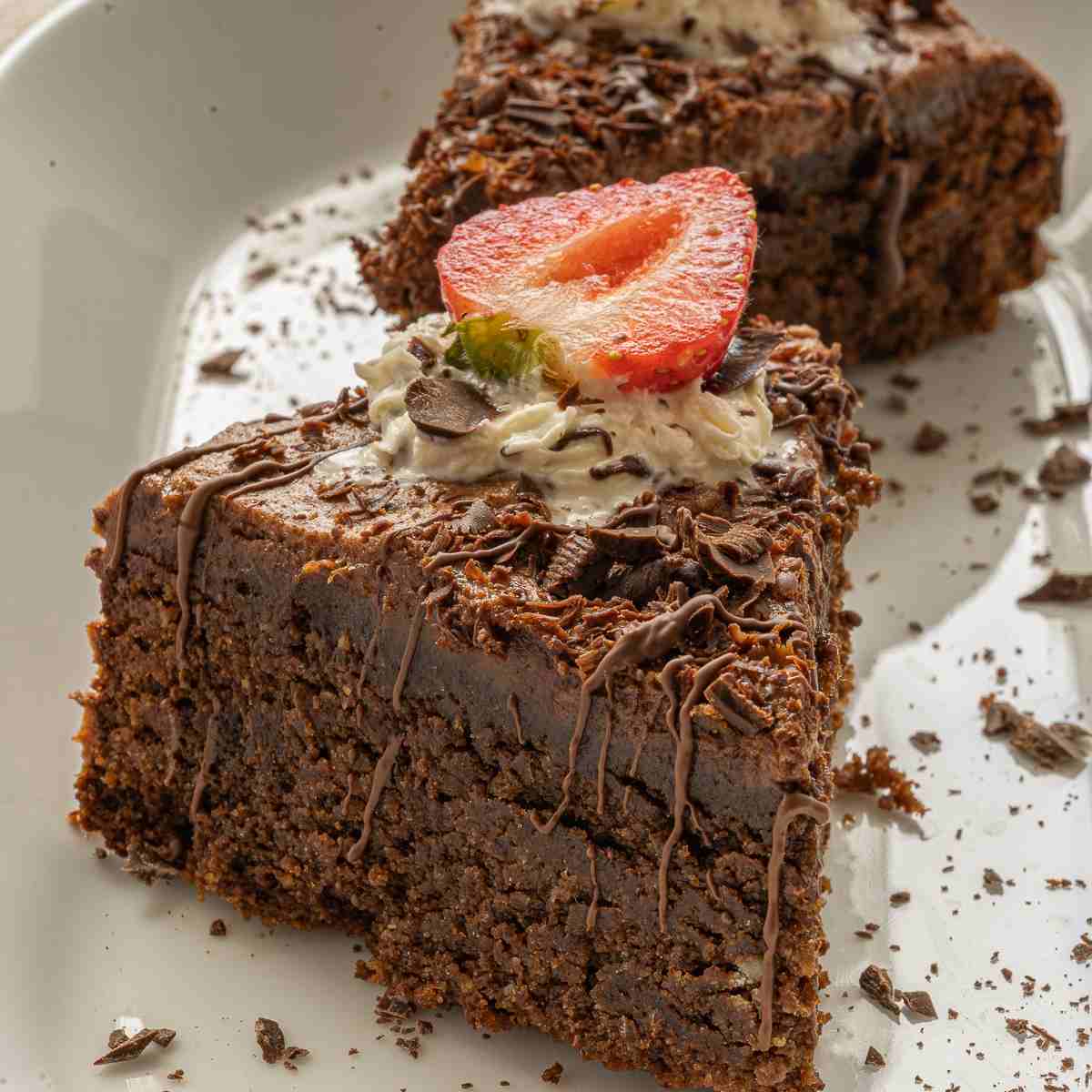 Two slices of chocolate cake with sliced strawberries on top.