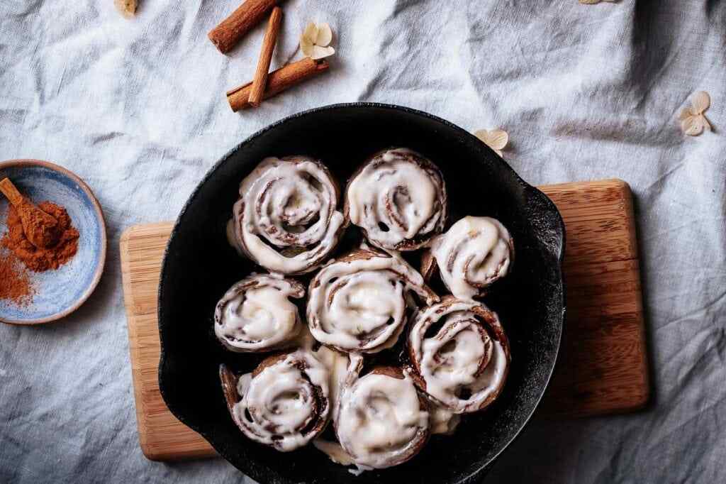 Buckwheat cinnamon rolls in a cast iron pan on a table.