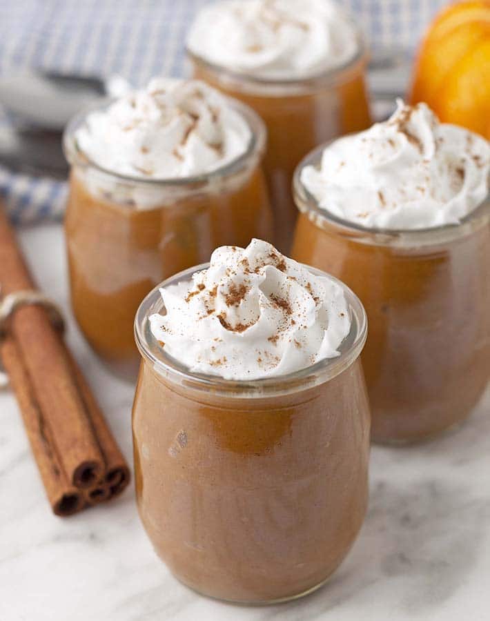 Sweet Potato Pudding in small glass jars with whipped cream on the top.