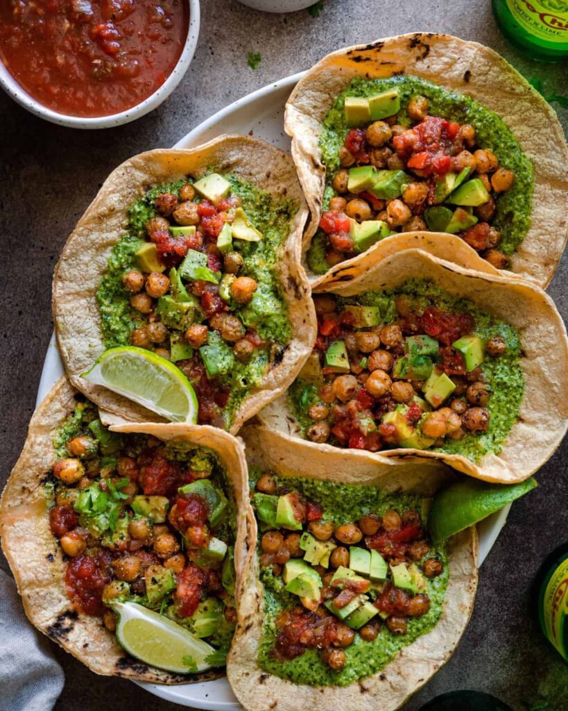 Chickpea tacos on a large platter with a red sauce in the corner.