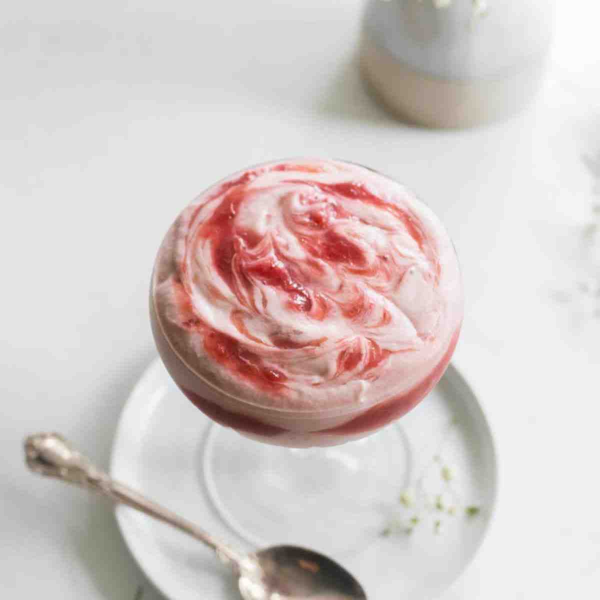 Rhubarb strawberry mousse in a cup with a spoon next to it.