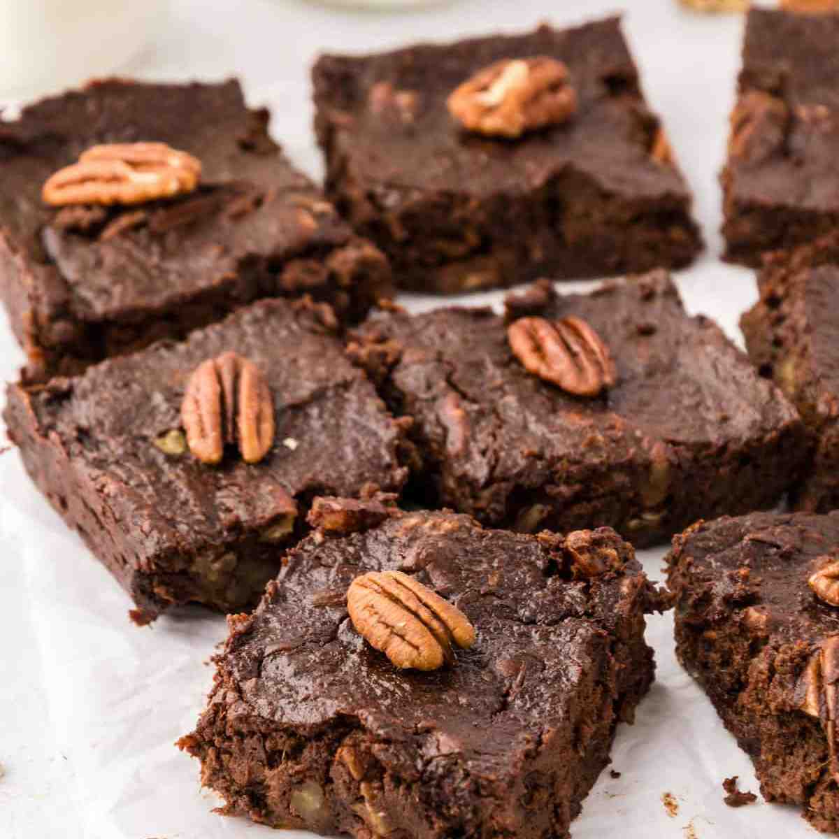 Sweet potato brownies with pecans on top of them on a white surface.