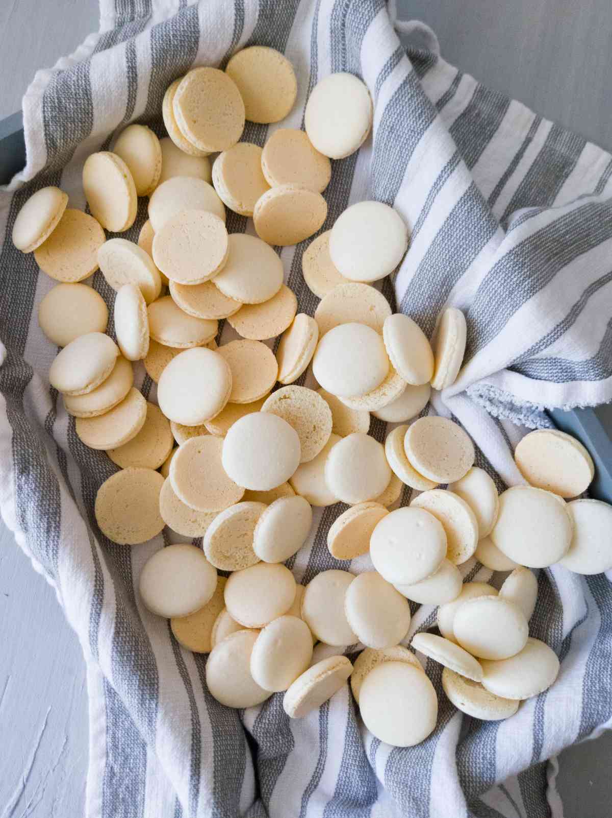 Macaron shells on a kitchen towel on a tray.