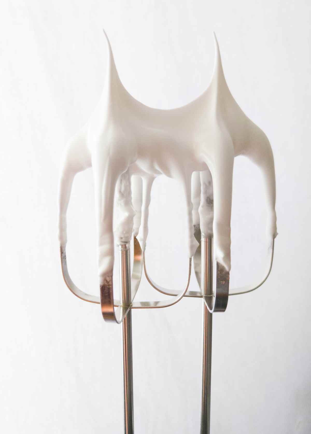 Two whisks with upward looking tips on a white background.