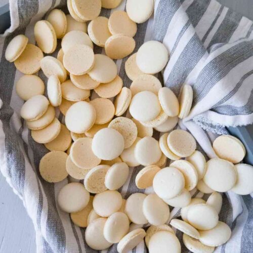 Swiss meringue macarons on a tray lined with a kitchen towel.