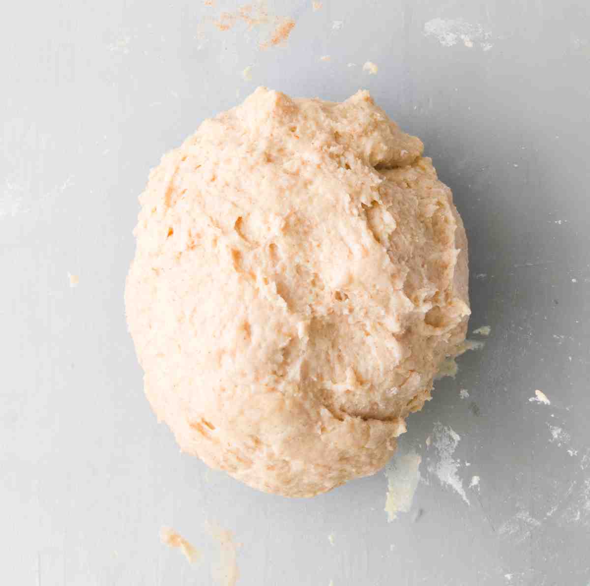 Pierogi dough shaped into a tight ball against a gray surface.