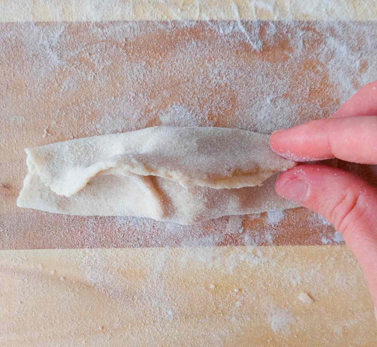 Pressing the sides of the dough together. 