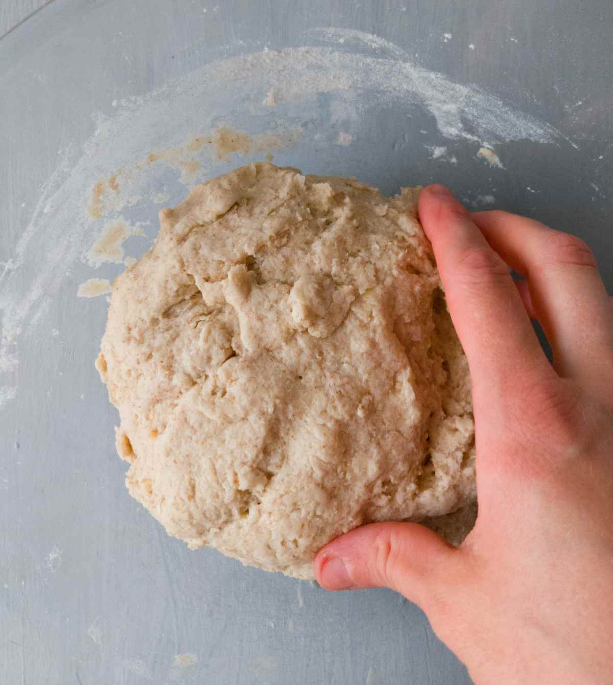 The dough shaped into a ball with a hand next to it.