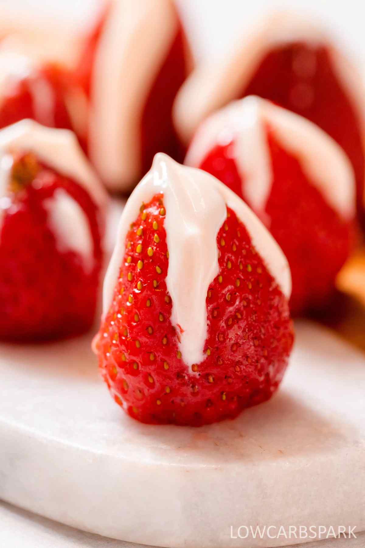 Strawberries stuffed with cheesecake on a white surface.