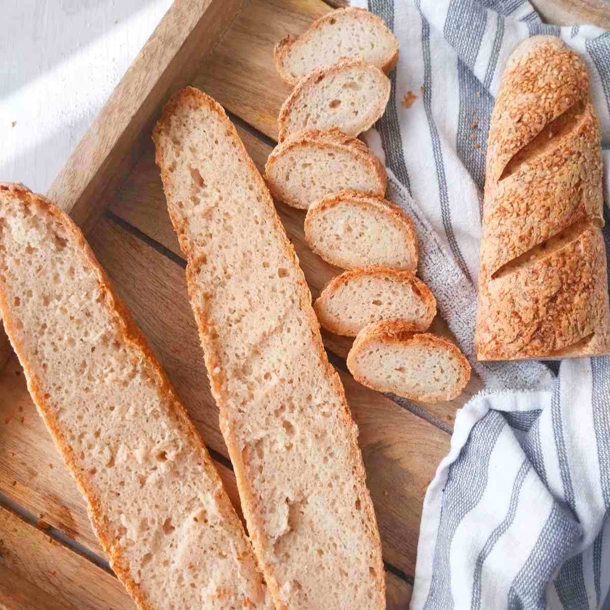 Gluten-free sourdough baguettes sliced on a wooden tray.