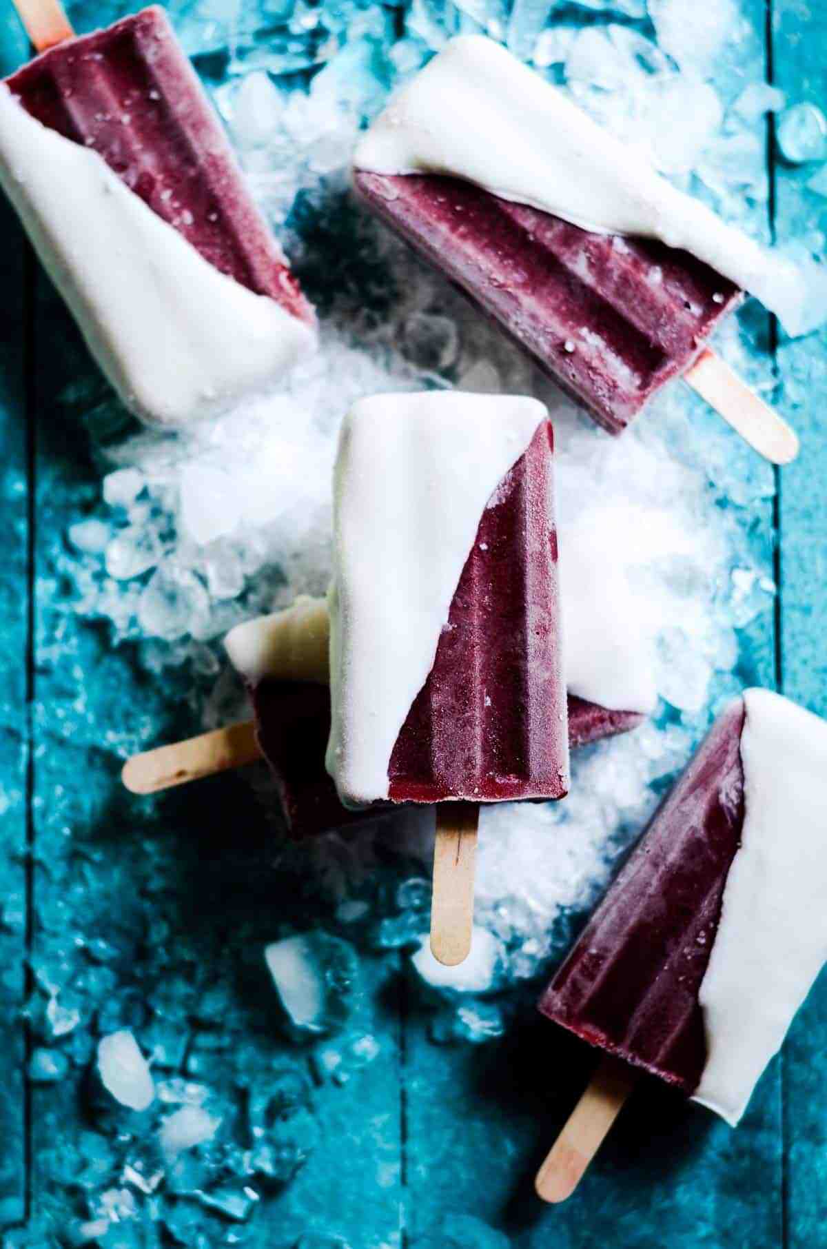 Cherry popsicles on a blue table surface.