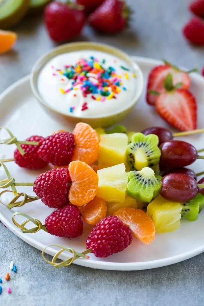 Fruit on skewers on a plate with a dip.