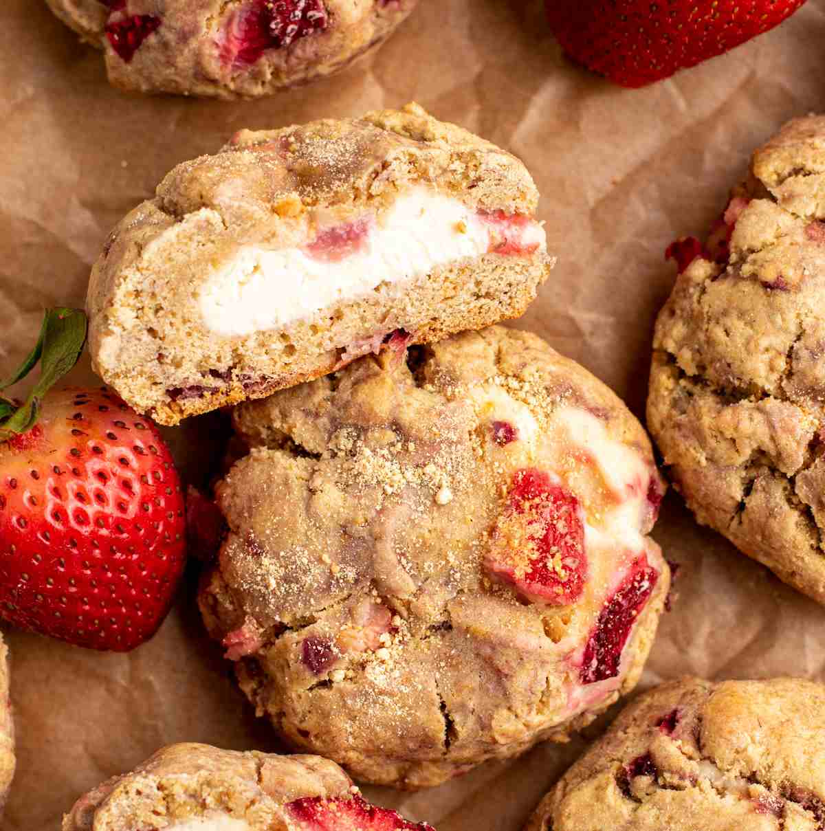 Strawberry cheesecake cookies cut and whole on parchment paper.