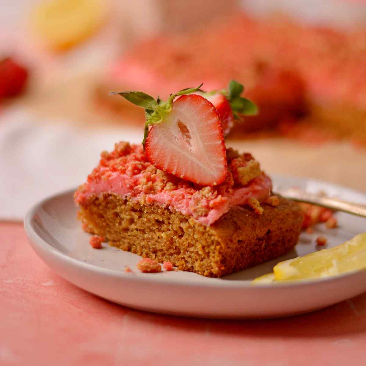 A clise of the cake with a sliced strawberry on the top on a white plate.