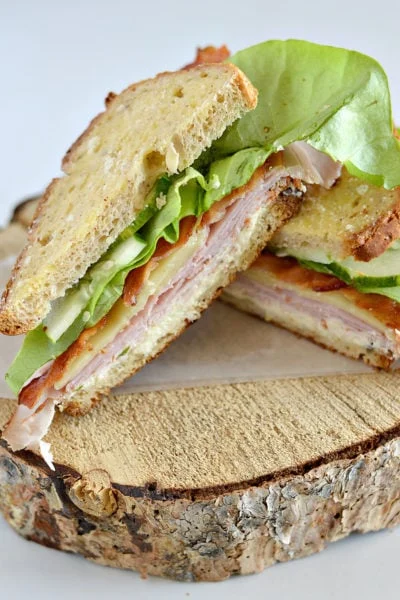 Turkey sandwich sliced and tilted on a wooden board.