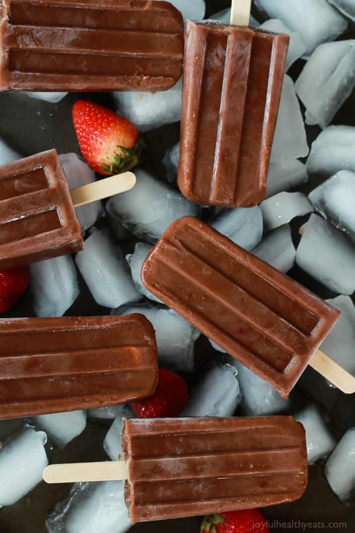 Chocolate banana popsicles on ice with fresh strawberries.