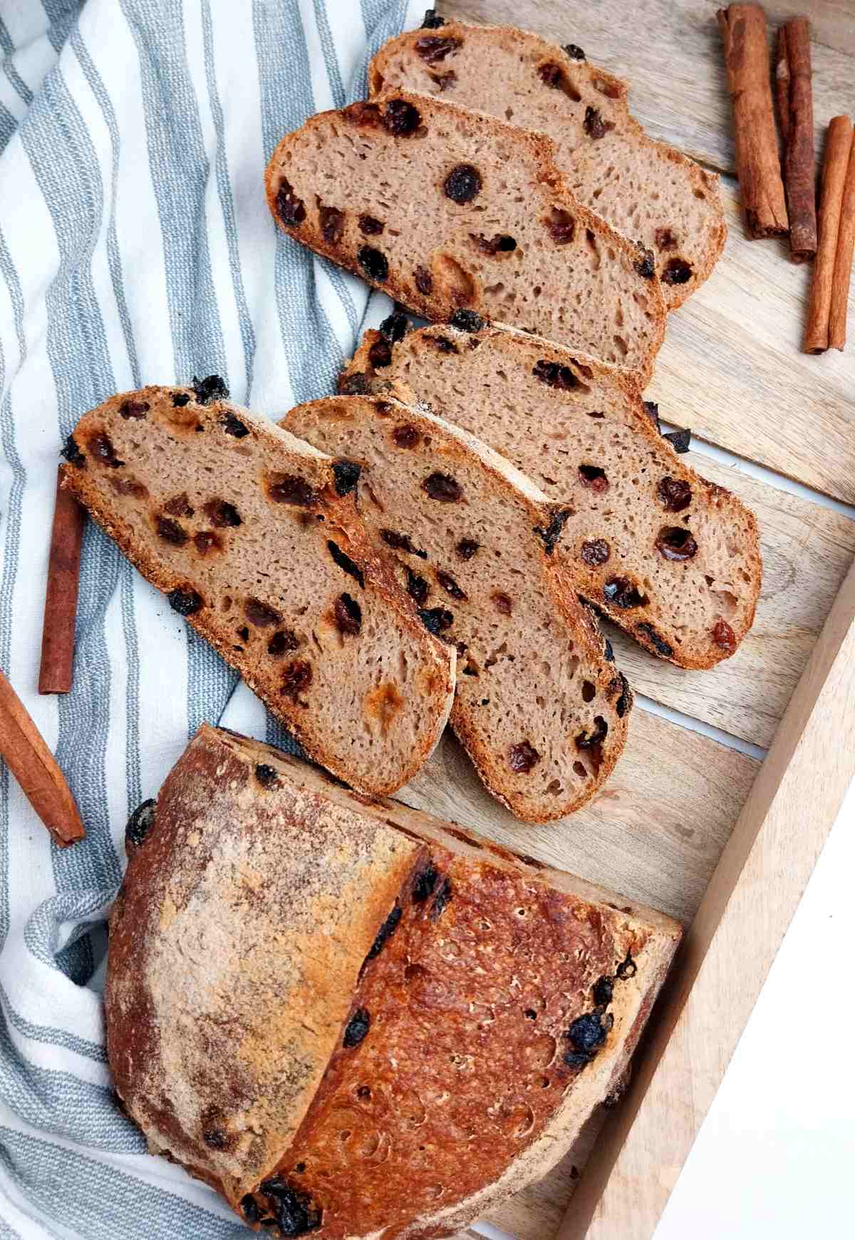 Sliced loaf on a wooden board with cinnamon sticks.