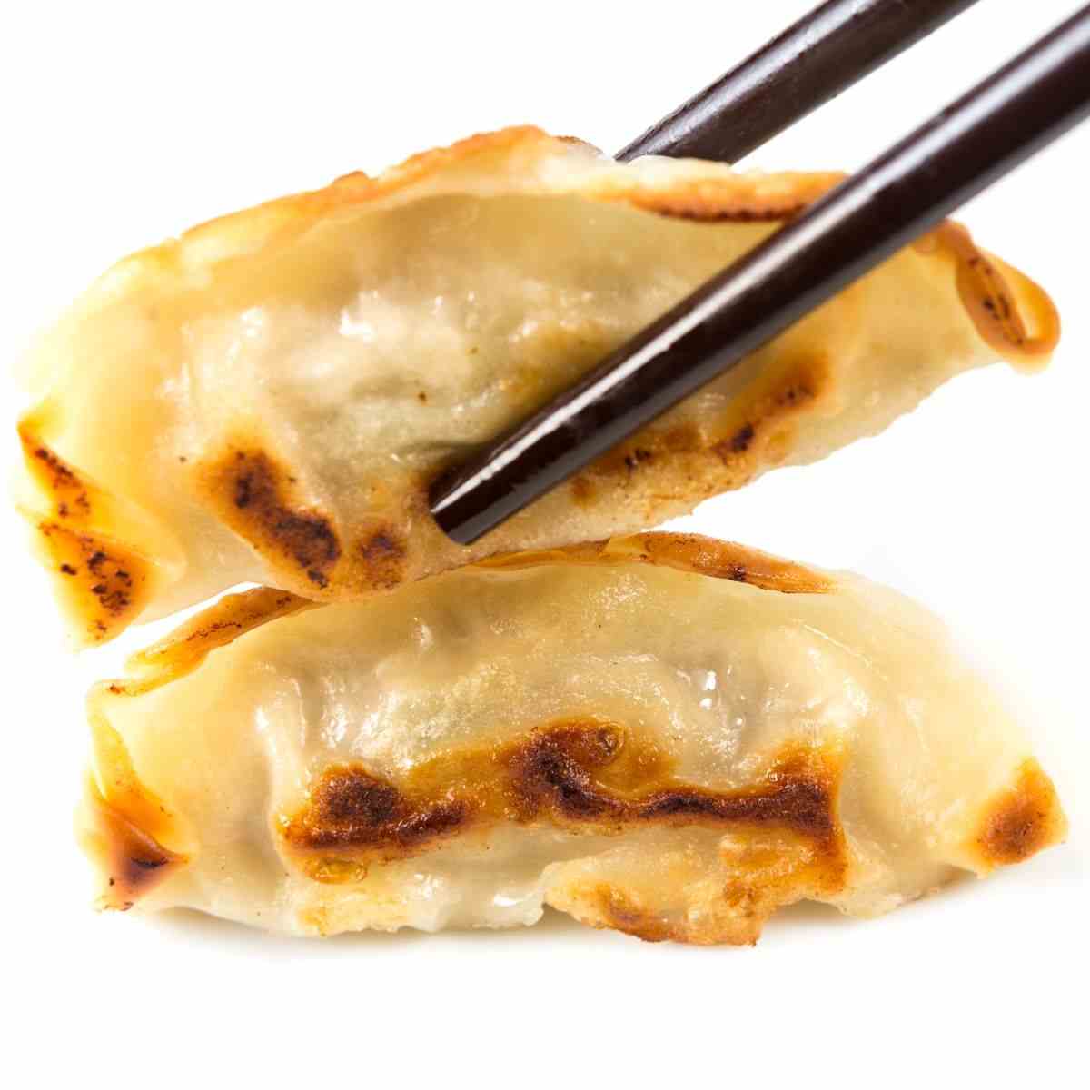 Japanese gyoza help by a chopstick with white background.