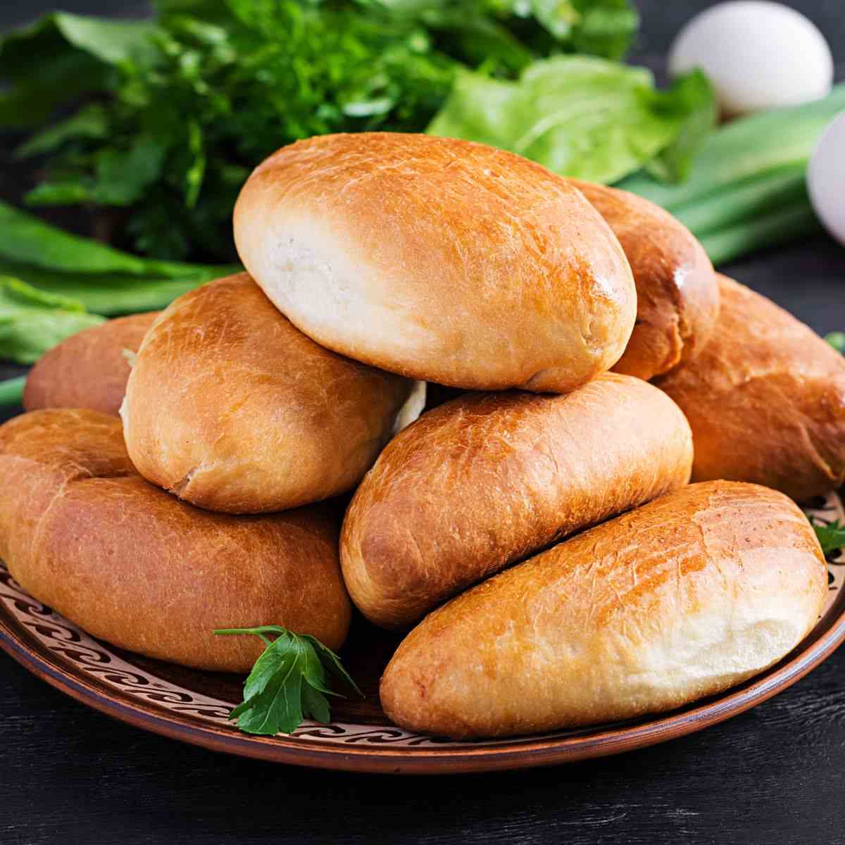 Piroshki on a plate with greens in the background.