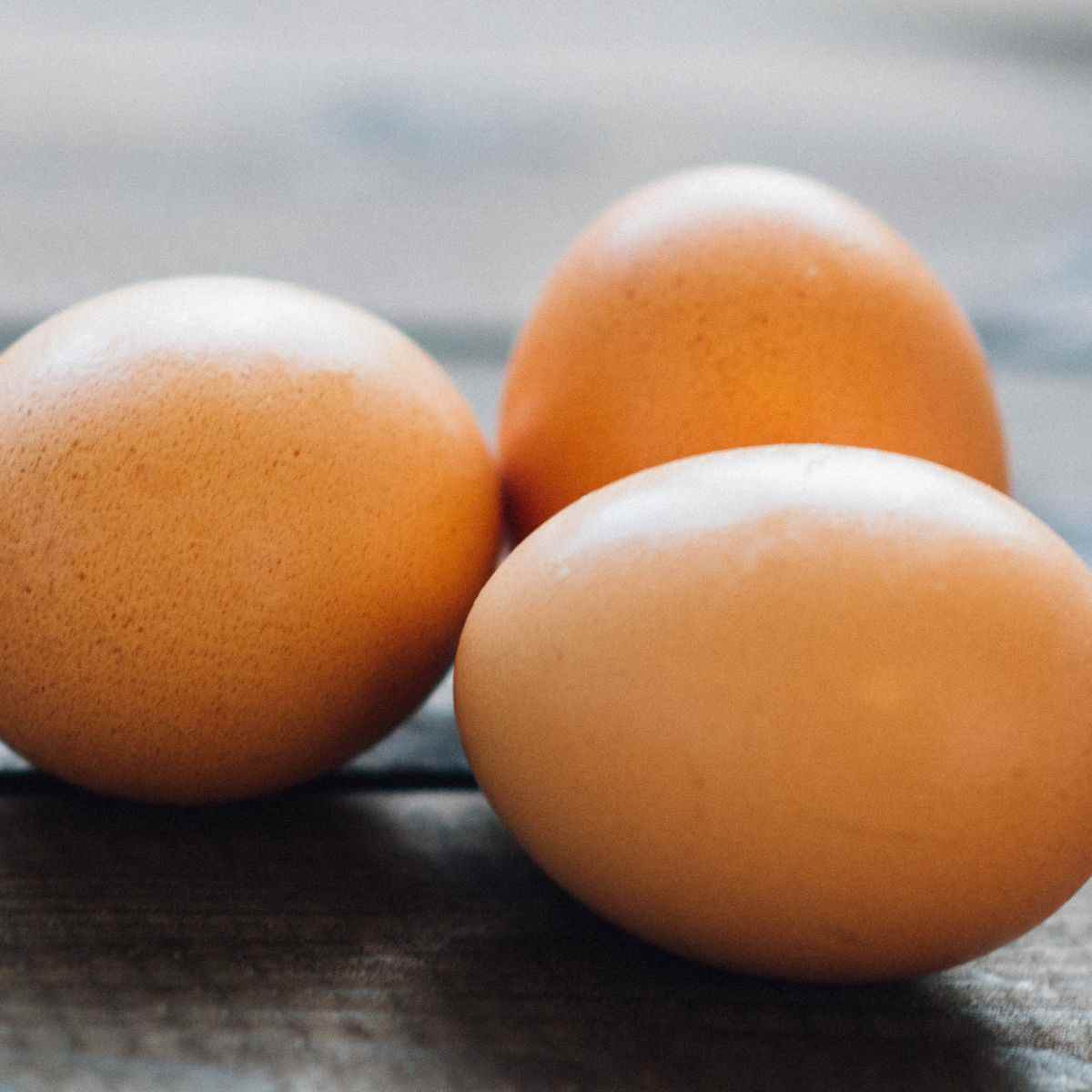 Three eggs on a wooden surface.