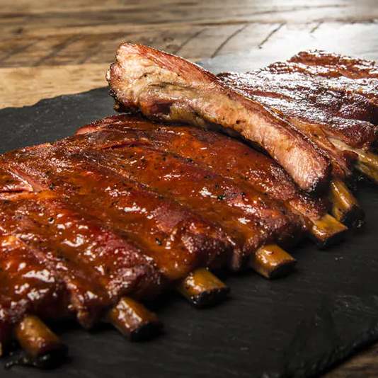 BBQ ribs on a black stone on a wooden table.