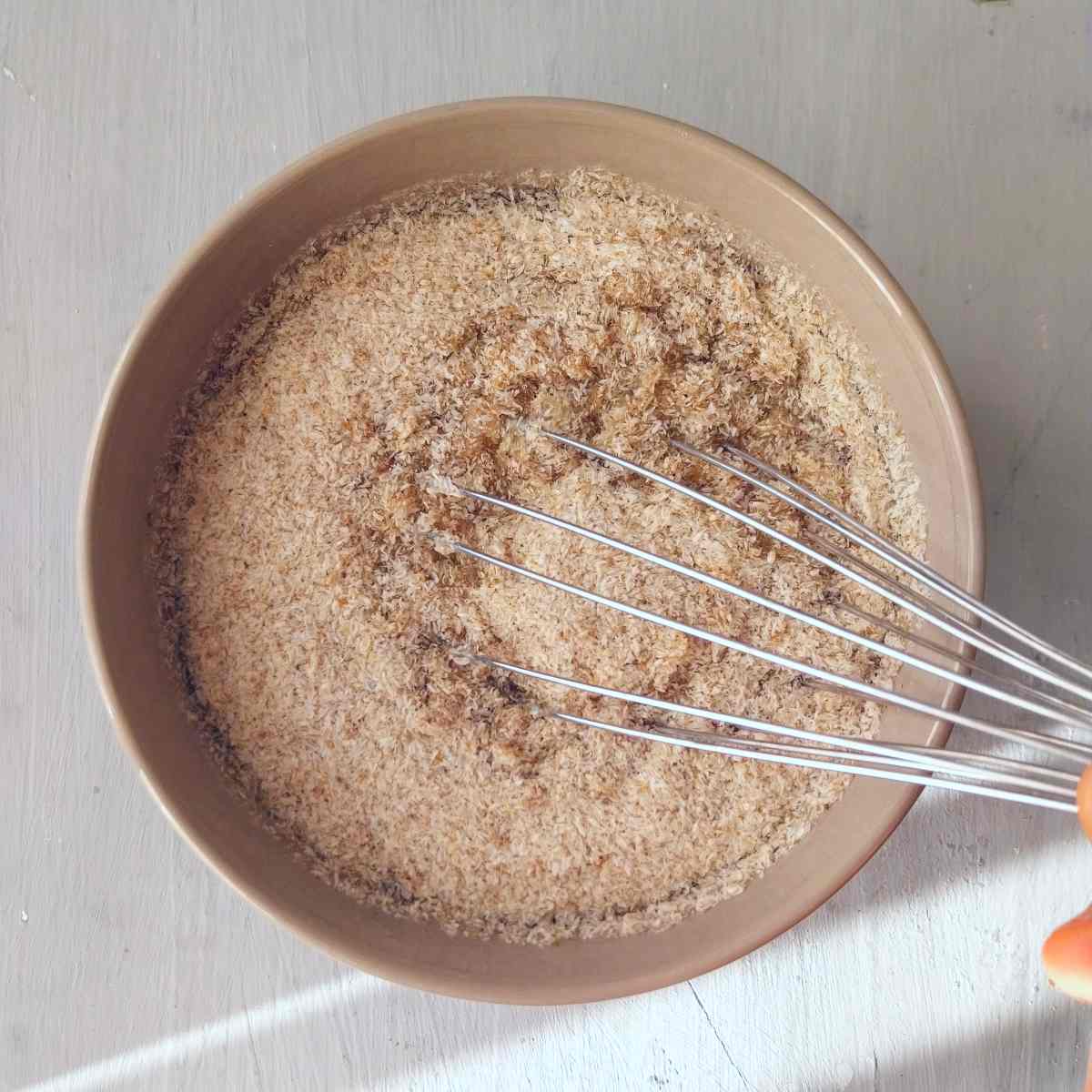 Psyllium husk in water with a whisk in a bowl.