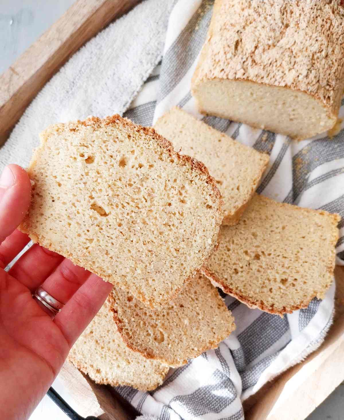 A slice of millet bread held by a hand with the bread in the background.