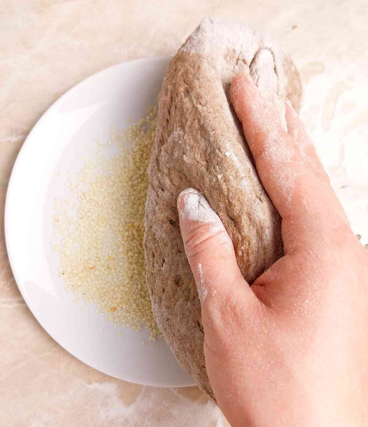 Dipping the dough into sesame seeds.