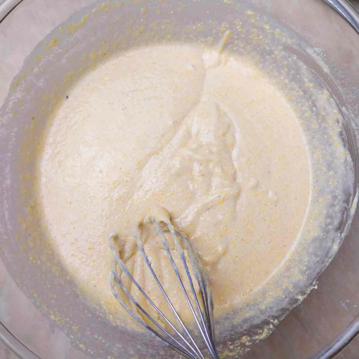 Cornbread dough mixed in a glass bowl.