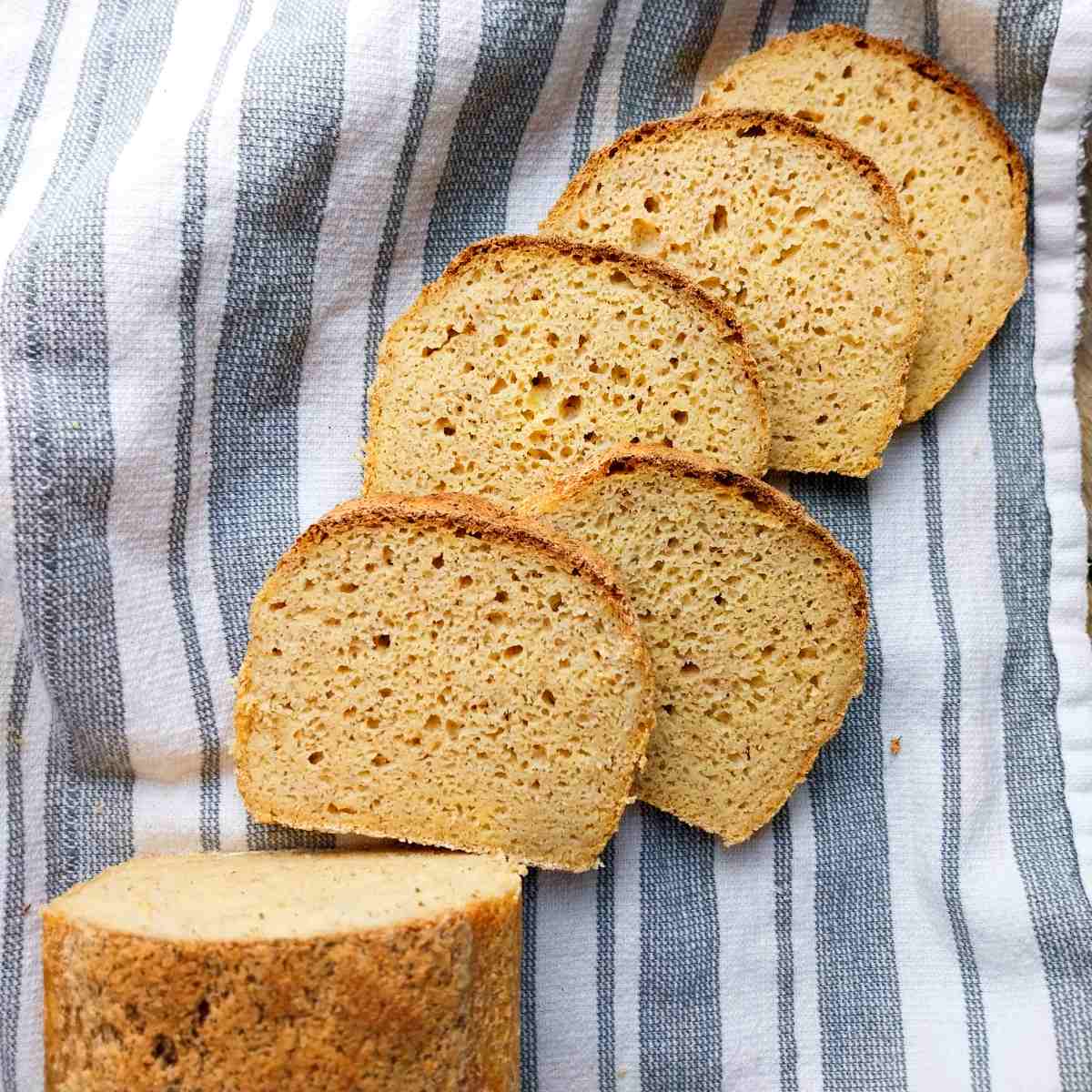 A loaf of millet bread sliced on a kitchen towel.