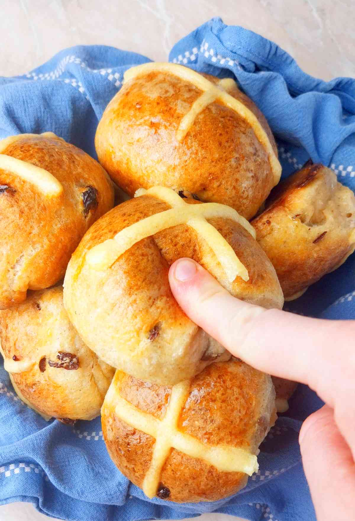 Gluten-free sourdough hot cross buns in a bowl and a kitchen towel.