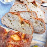 Gluten-free cheddar jalapeno sourdough sliced on a wooden surface.