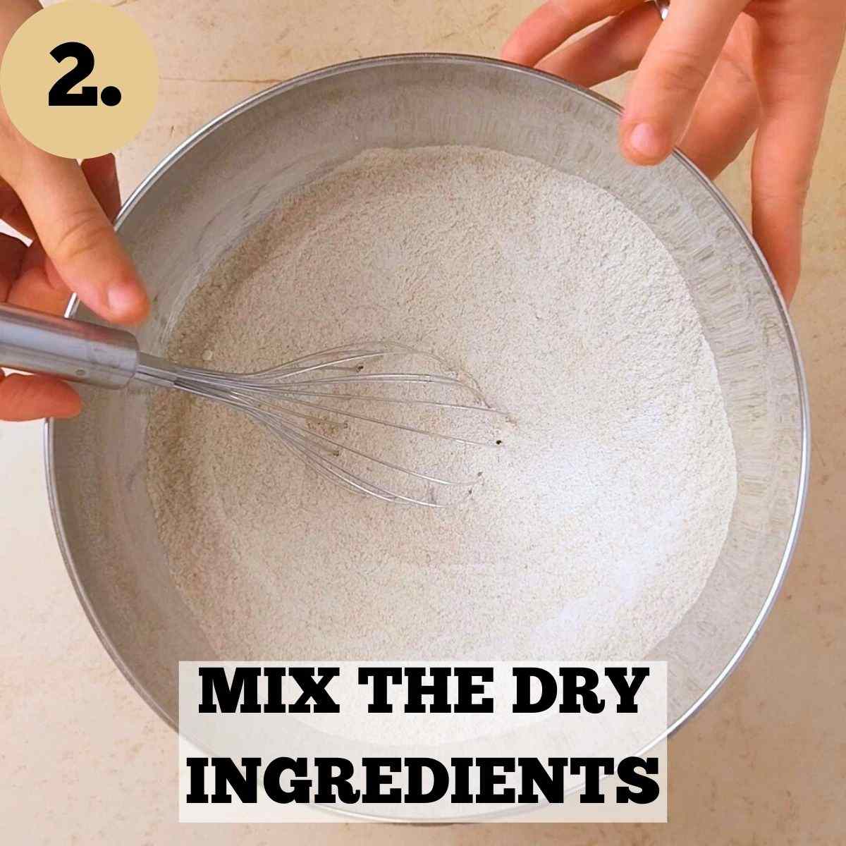 Mixing the dry ingredients with a whisk in a metal mixing bowl.