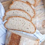 Slices of gluten-free Dutch oven bread on a wooden surface lined with a kitchen towel.