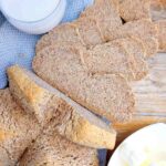Soda bread sliced on a wooden surface with a blue kitchen towel.