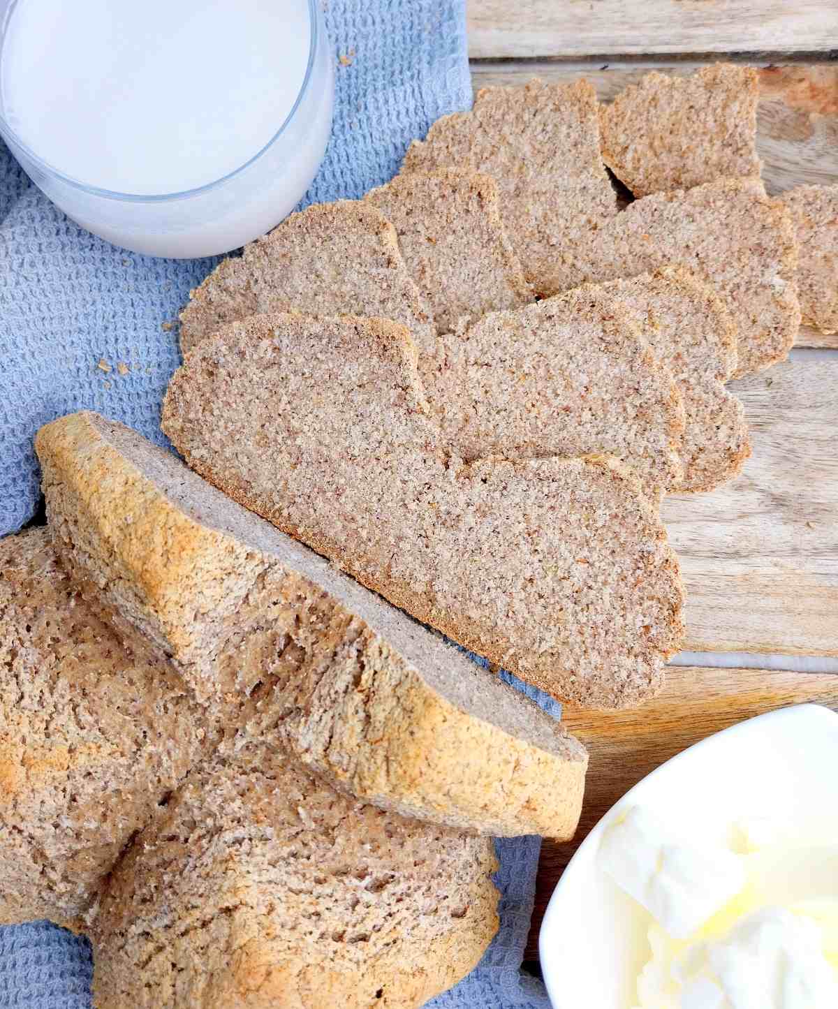 Soda bread sliced on a wooden surface with a blue kitchen towel.