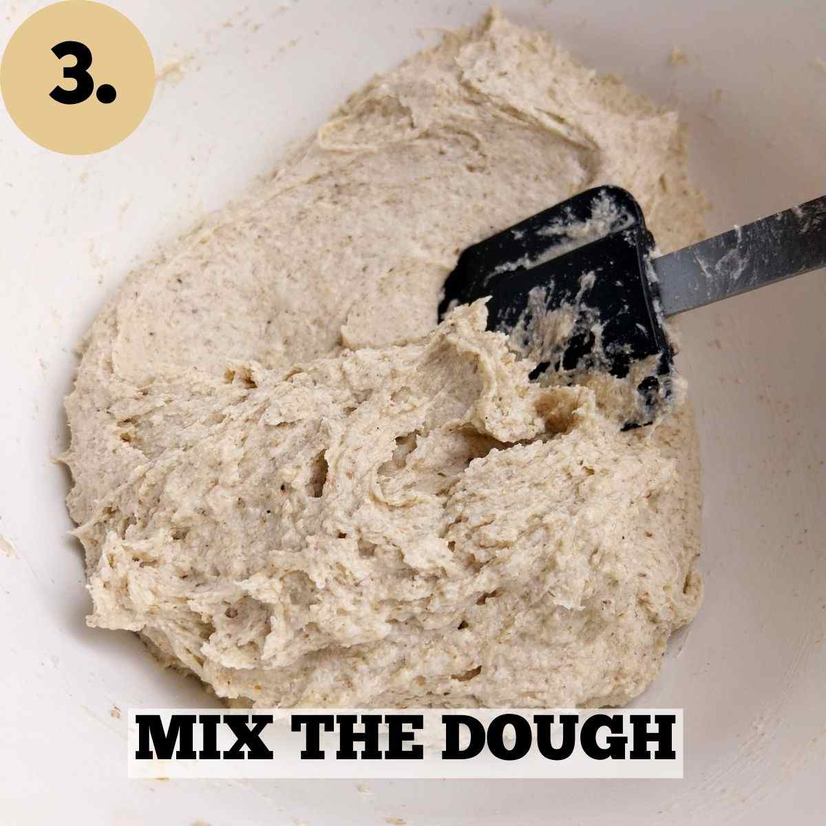 Mixed buckwheat rolls dough in a glass bowl with a spatula.